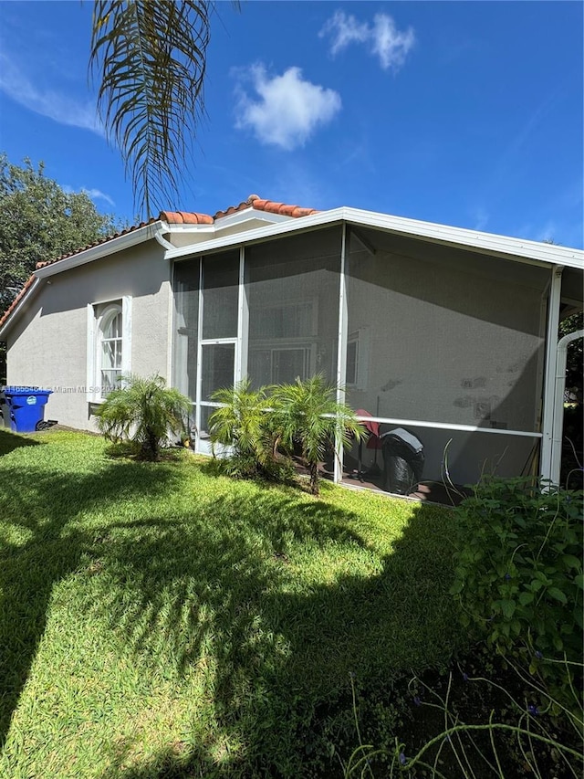 view of side of property featuring a yard and a sunroom