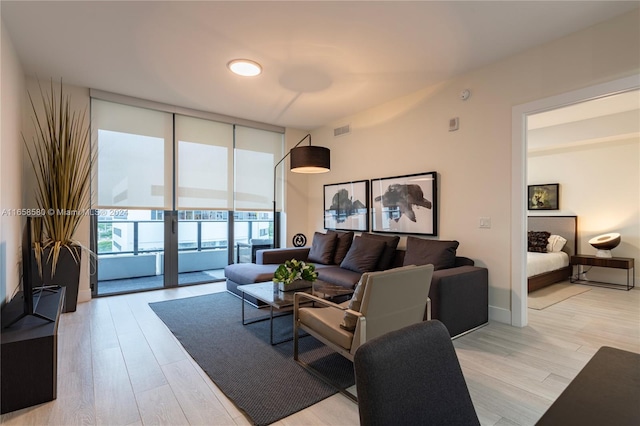 living room featuring a wall of windows and light hardwood / wood-style floors