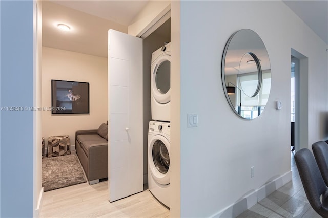 clothes washing area featuring stacked washer / drying machine and light hardwood / wood-style floors