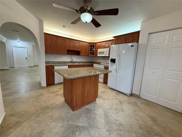 kitchen featuring ceiling fan, a kitchen island, white appliances, and sink