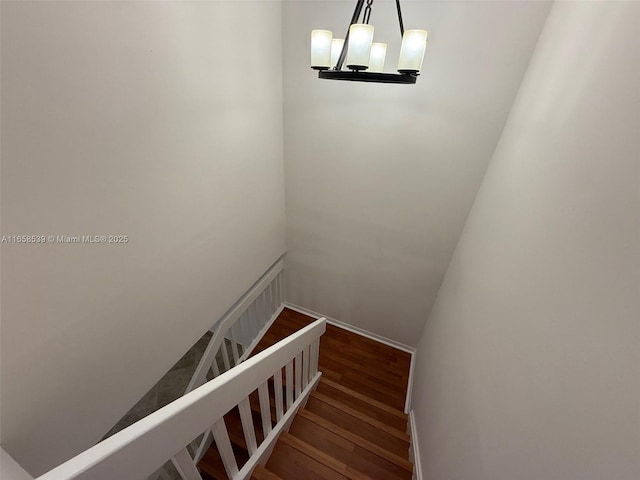 staircase featuring hardwood / wood-style floors and an inviting chandelier