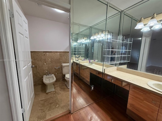 bathroom featuring vanity, toilet, tile walls, and a bidet