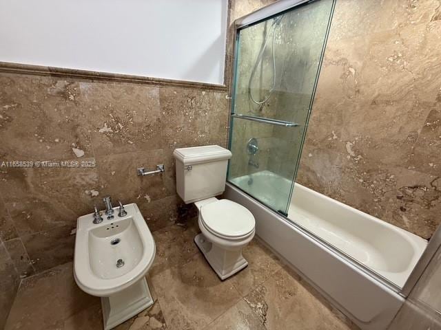 bathroom with a bidet, combined bath / shower with glass door, tile walls, and toilet