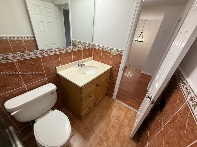 bathroom featuring vanity, toilet, and tile walls