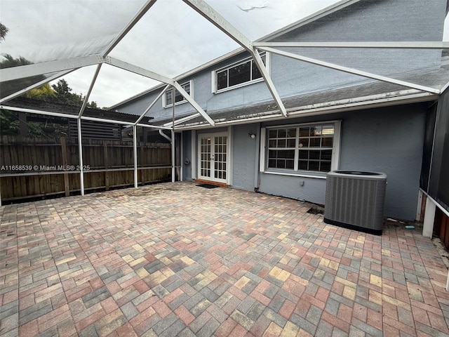 view of patio featuring french doors, glass enclosure, and central air condition unit