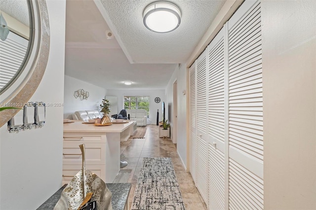 hall featuring a textured ceiling and light tile patterned floors