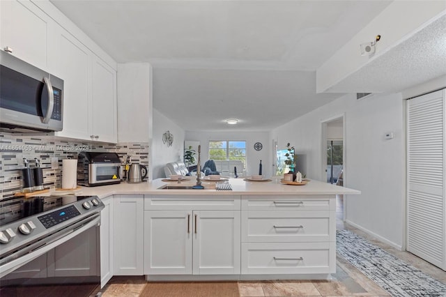 kitchen with white cabinets, backsplash, stainless steel appliances, and kitchen peninsula