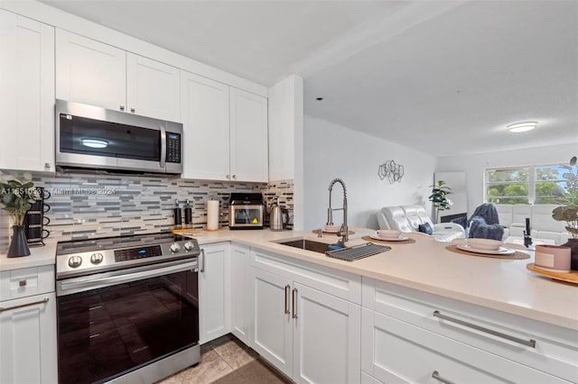 kitchen with appliances with stainless steel finishes, white cabinetry, sink, and decorative backsplash