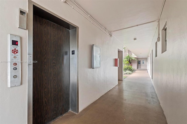 corridor with elevator and concrete floors