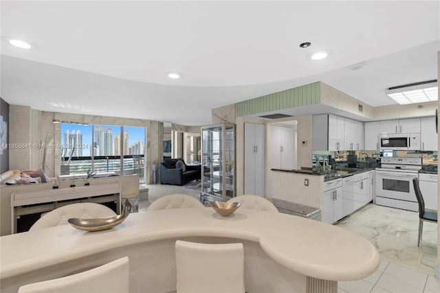 kitchen with decorative backsplash, white cabinets, and white appliances