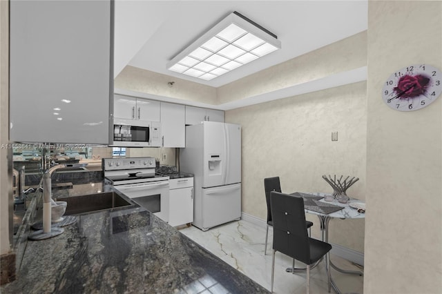 kitchen with dark stone counters, white appliances, white cabinetry, and sink