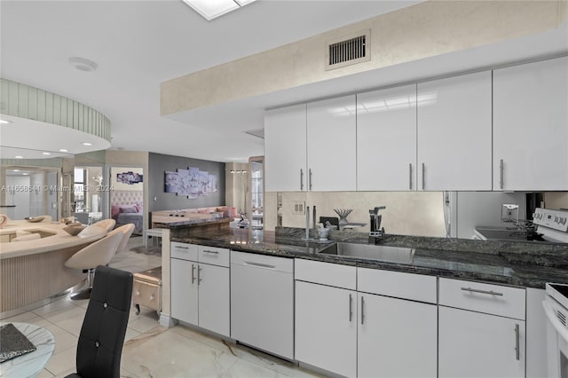 kitchen with white cabinets, dark stone countertops, and sink