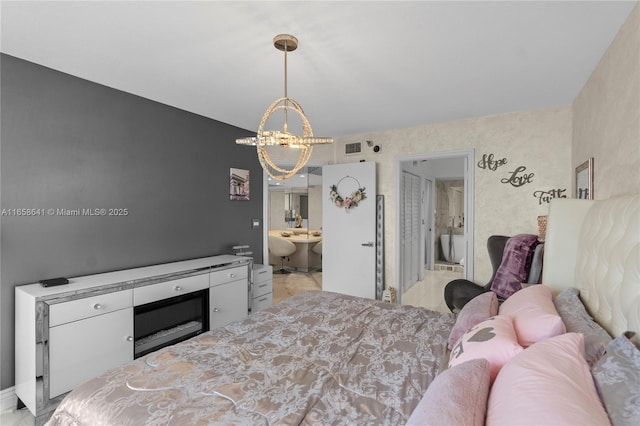 bedroom with connected bathroom, a notable chandelier, and light tile patterned flooring