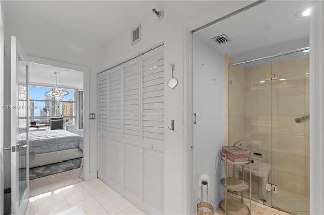 bathroom featuring a shower with door, a chandelier, and tile patterned floors