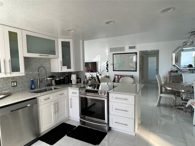 kitchen with appliances with stainless steel finishes, light stone countertops, sink, and white cabinets