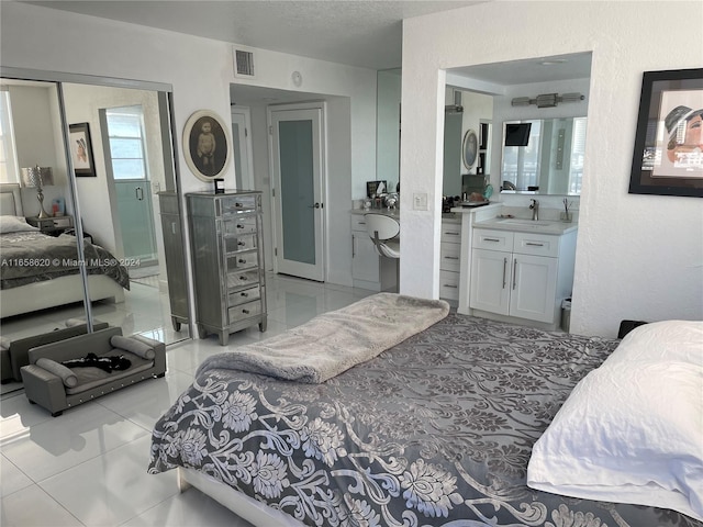 tiled bedroom featuring a textured ceiling, sink, and a closet