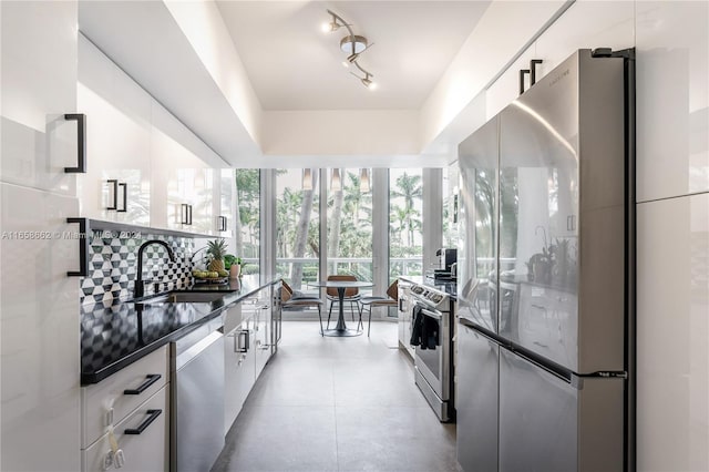 kitchen featuring decorative backsplash, stainless steel appliances, white cabinetry, and sink