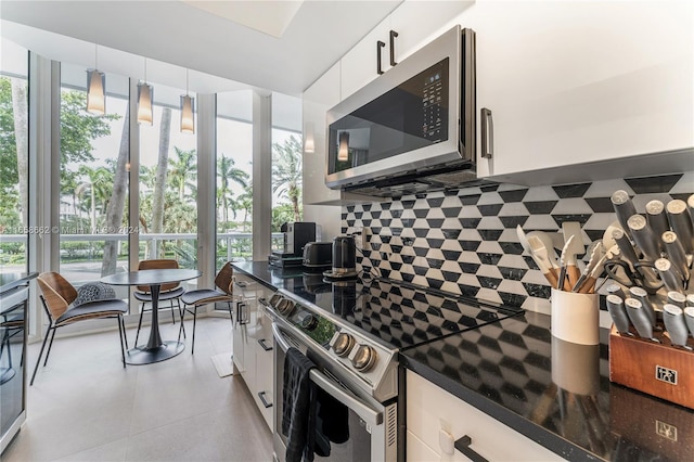 kitchen featuring dark stone counters, white cabinets, decorative light fixtures, and stainless steel appliances