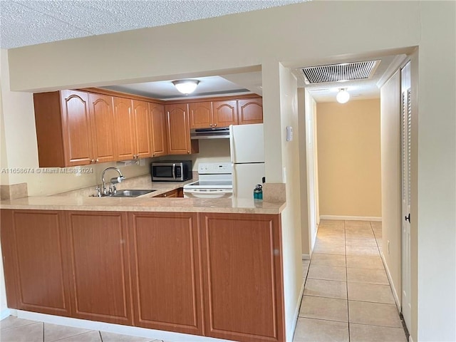 kitchen with white appliances, a textured ceiling, light tile patterned floors, kitchen peninsula, and sink