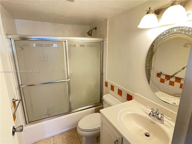 full bathroom featuring shower / bath combination with glass door, vanity, toilet, tile patterned floors, and decorative backsplash