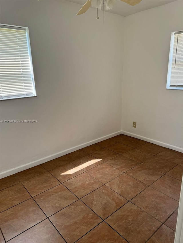 tiled empty room featuring ceiling fan and a healthy amount of sunlight