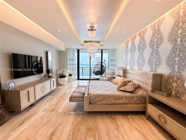 bedroom featuring a chandelier, a wall of windows, a tray ceiling, and access to outside
