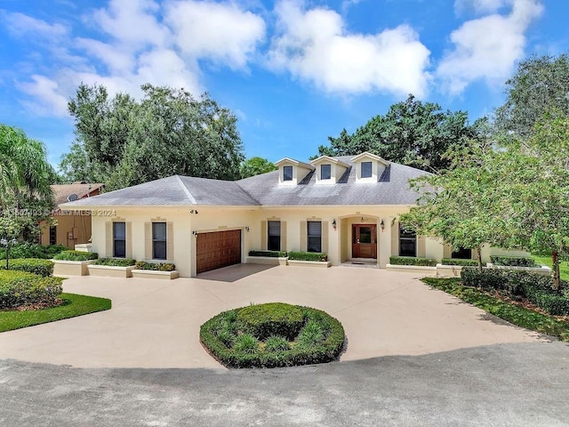 view of front of property with a garage, stucco siding, and curved driveway