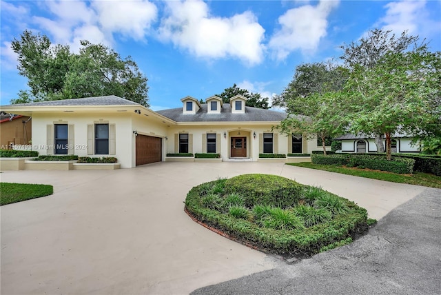 view of front of property with an attached garage, stucco siding, and curved driveway
