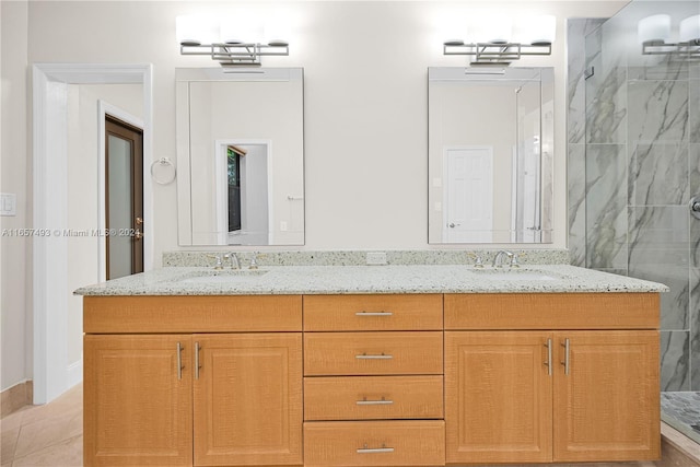 full bathroom with a marble finish shower, a sink, and double vanity