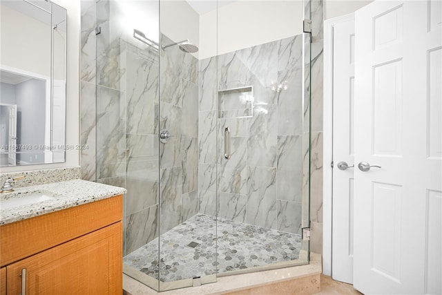 bathroom featuring a marble finish shower and vanity