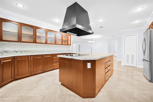 kitchen with a textured ceiling, island exhaust hood, black electric stovetop, ornamental molding, and freestanding refrigerator