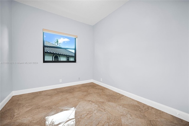 empty room with vaulted ceiling and baseboards