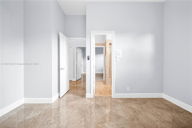 unfurnished bedroom featuring marble finish floor and baseboards