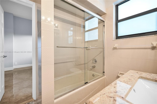 bathroom featuring vanity, tile walls, and enclosed tub / shower combo