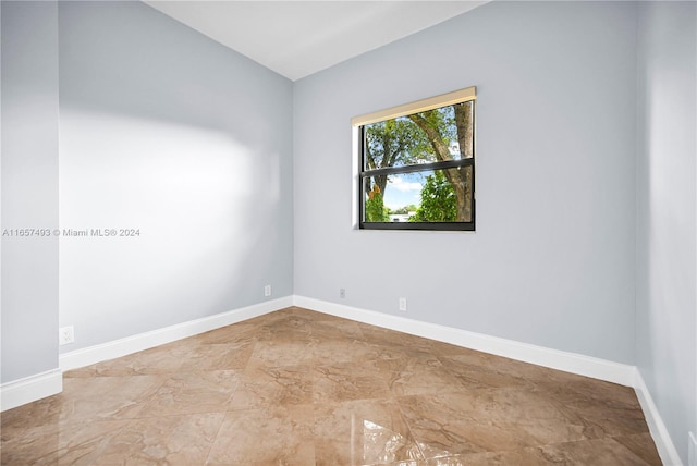 spare room featuring marble finish floor and baseboards