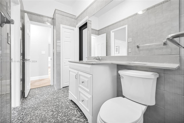 bathroom featuring vanity, toilet, and tile walls