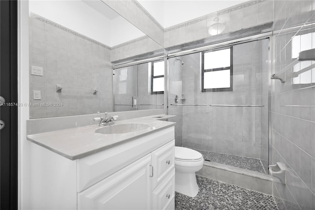 bathroom featuring tile patterned flooring, toilet, a shower with door, and vanity