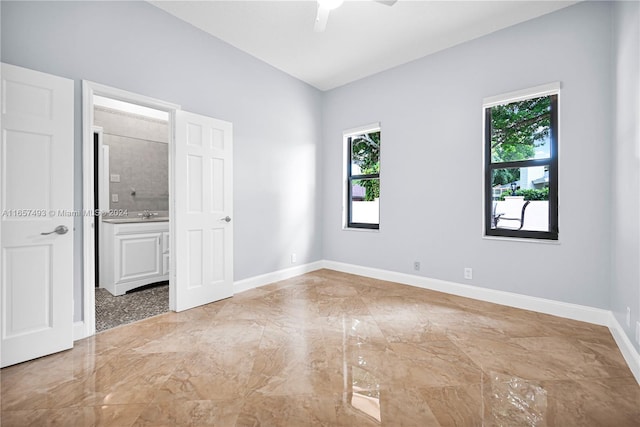 spare room featuring baseboards, a ceiling fan, marble finish floor, and a healthy amount of sunlight