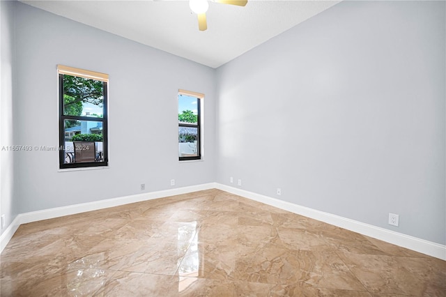 empty room with a ceiling fan, baseboards, and marble finish floor