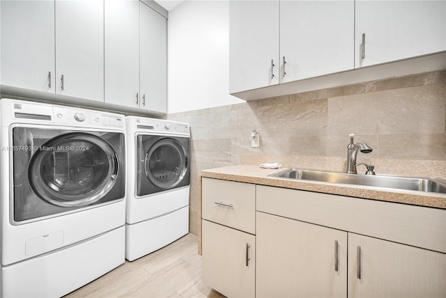 washroom with cabinets, washing machine and dryer, and sink