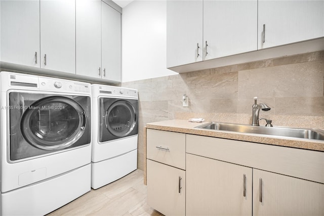 laundry area with washing machine and dryer, cabinet space, and a sink