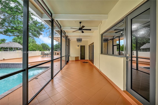 unfurnished sunroom featuring ceiling fan and beam ceiling