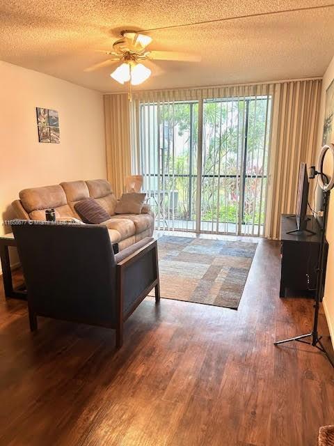 living room with a textured ceiling, dark hardwood / wood-style floors, and ceiling fan