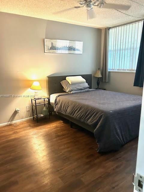 bedroom featuring ceiling fan, dark wood-type flooring, and a textured ceiling