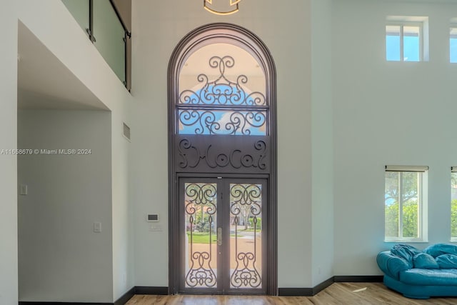 foyer entrance with a high ceiling, light wood-type flooring, and french doors