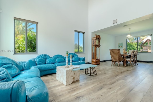 living room featuring light wood-type flooring, a wealth of natural light, and a high ceiling