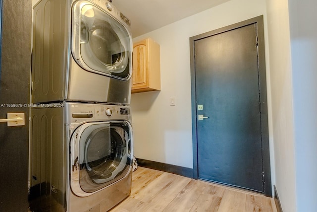 clothes washing area with light wood-type flooring, stacked washer and clothes dryer, and cabinets