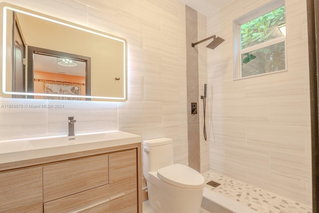 bathroom with toilet, a tile shower, tile walls, tasteful backsplash, and vanity