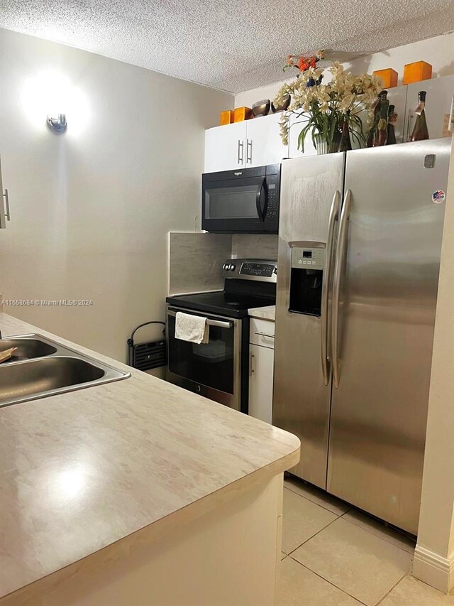 kitchen featuring light tile patterned floors, stainless steel appliances, white cabinetry, and sink