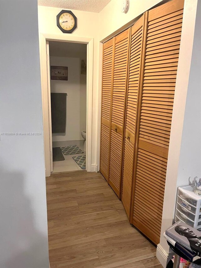 hall featuring a textured ceiling and light hardwood / wood-style floors